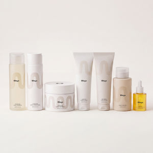 A set of seven Wingei skincare products arranged in a row against a clean, off-white background. The products include various bottles, jars, and tubes in minimalist white and beige packaging with black text.